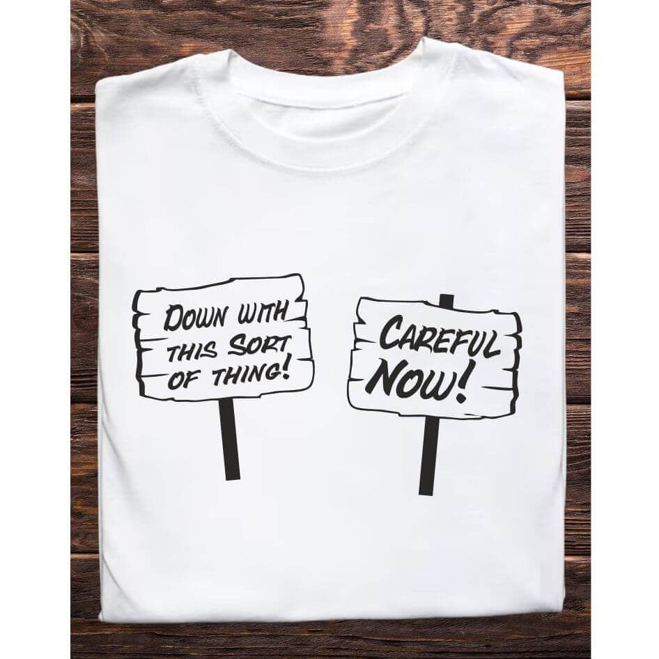 Father Ted Themed Careful Now Tee Shirt from Joke.ie, Ireland. Celebrate the unforgettable humor of Father Ted with our exclusive Careful Now Tee Shirt, inspired by the hilarious protest scene from the episode "The Passion of St. Tibulus." Perfect for fans who adore the series' witty satire and iconic moments, this t-shirt is a must-have for any Father Ted enthusiast. Design and Style The Careful Now Tee Shirt features a vibrant and comical design that captures the essence of the memorable protest led by Father Ted and Father Dougal. The front of the shirt showcases two prominent signs: one reading "Careful Now" and the other boldly declaring "Down with this Sort of Thing." These phrases are illustrated in a bold, eye-catching style that mirrors the hand-drawn look from the show, making it instantly recognizable to fans. Material and Comfort Crafted from high-quality, 100% cotton, this t-shirt offers exceptional comfort and durability. The fabric is soft, breathable, and perfect for everyday wear. Pre-shrunk to ensure a consistent fit, this t-shirt maintains its shape and size after multiple washes, providing long-lasting enjoyment. Humorous and Nostalgic Wearing the "Careful Now" T-Shirt is a delightful way to pay homage to the comedic genius of Father Ted. The design evokes laughter and fond memories of the show's classic episode, "The Passion of St. Tibulus," where Ted and Dougal's feeble protest becomes an iconic moment in TV history. It's a subtle yet effective way to showcase your love for the series and connect with other fans. Versatile and Stylish This t-shirt is versatile enough to pair with jeans, shorts, or even pajama bottoms for a relaxed, casual look. Its classic fit makes it suitable for any occasion, whether you're attending a comedy show, hanging out with friends, or simply relaxing at home. The humorous design ensures you'll stand out and spark conversations wherever you go. Perfect Gift for Fans Looking for the ideal gift for a Father Ted aficionado? The "Careful Now" T-Shirt is a fantastic choice. Its unique design and superior quality make it a thoughtful and enjoyable present for birthdays, holidays, or any special occasion. Celebrate the wit and nostalgia of Father Ted with the Careful Now Tee Shirt. Featuring the iconic protest signs "Careful Now" and "Down with this Sort of Thing" from "The Passion of St. Tibulus" episode, this shirt is a must-have for any fan of the show. Enjoy the comfort of premium cotton and the joy of sharing your favorite TV moments with the world. Get your "Careful Now" T-Shirt today and add a touch of Craggy Island humor to your wardrobe! Colour: White loose fit tee Size: Small 35/37″ Medium 38/40″ Large 41/43″ X Large 44/46″ 2X Large 47/49″ 3X Large 50/522 View our entire Father Ted Collection here.