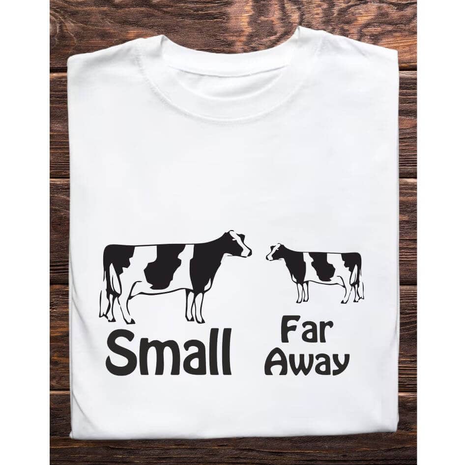 Father Ted Themed Small Far Away Tee Shirt from Joke.ie, Ireland. Celebrate one of the most iconic and hilarious scenes from Father Ted with our Small Far Away Tee Shirt. Perfect for fans who love the series' unique brand of humor, this t-shirt captures the unforgettable moment when Father Ted tries to explain perspective to Father Dougal. Design and Style The Small Far Away Tee Shirt features a clever design that brings to life the classic scene from the show. The front of the shirt displays two images of cows: one cow is small, and the other is larger. Below these images, the phrase "Small" is written under the small cow, and "Far Away" is written under the larger cow, mimicking Father Ted's explanation of perspective to Dougal. The design is rendered in a playful, cartoonish style that is instantly recognizable to fans of the show. Material and Comfort Made from premium-quality, 100% cotton, this t-shirt offers exceptional comfort and durability. The soft, breathable fabric ensures a cozy fit, perfect for everyday wear or special occasions. The material is pre-shrunk, so it maintains its shape and size even after multiple washes, ensuring long-lasting wear. Humorous and Nostalgic Wearing the "Small Far Away" T-Shirt is a delightful way to celebrate the witty and memorable humor of Father Ted. The design instantly evokes laughter and fond memories of the show's classic moments. It's a subtle yet effective way to showcase your love for the series and connect with fellow fans who recognize the reference. Versatile and Stylish This t-shirt pairs well with jeans, shorts, or even pajama bottoms for a relaxed, casual look. Its classic fit makes it suitable for any occasion, whether you’re heading to a comedy night, hanging out with friends, or simply relaxing at home. The humorous design ensures you'll stand out and spark conversations wherever you go. Perfect Gift for Fans Looking for the perfect gift for a Father Ted aficionado? The "Small Far Away" T-Shirt is an excellent choice. Its unique design and high-quality construction make it a thoughtful and enjoyable present for birthdays, holidays, or any special occasion. Celebrate the wit and nostalgia of Father Ted with the "Small Far Away" T-Shirt. Featuring the iconic scene where Father Ted explains perspective to Dougal, this shirt is a must-have for any fan of the show. Enjoy the comfort of premium cotton and the joy of sharing your favorite TV moments with the world. Get your "Small Far Away" T-Shirt today and add a touch of Craggy Island humor to your wardrobe! Colour: White loose fit tee Size: Small 35/37″ Medium 38/40″ Large 41/43″ X Large 44/46″ 2X Large 47/49″ 3X Large 50/522 View our entire Father Ted Collection here.